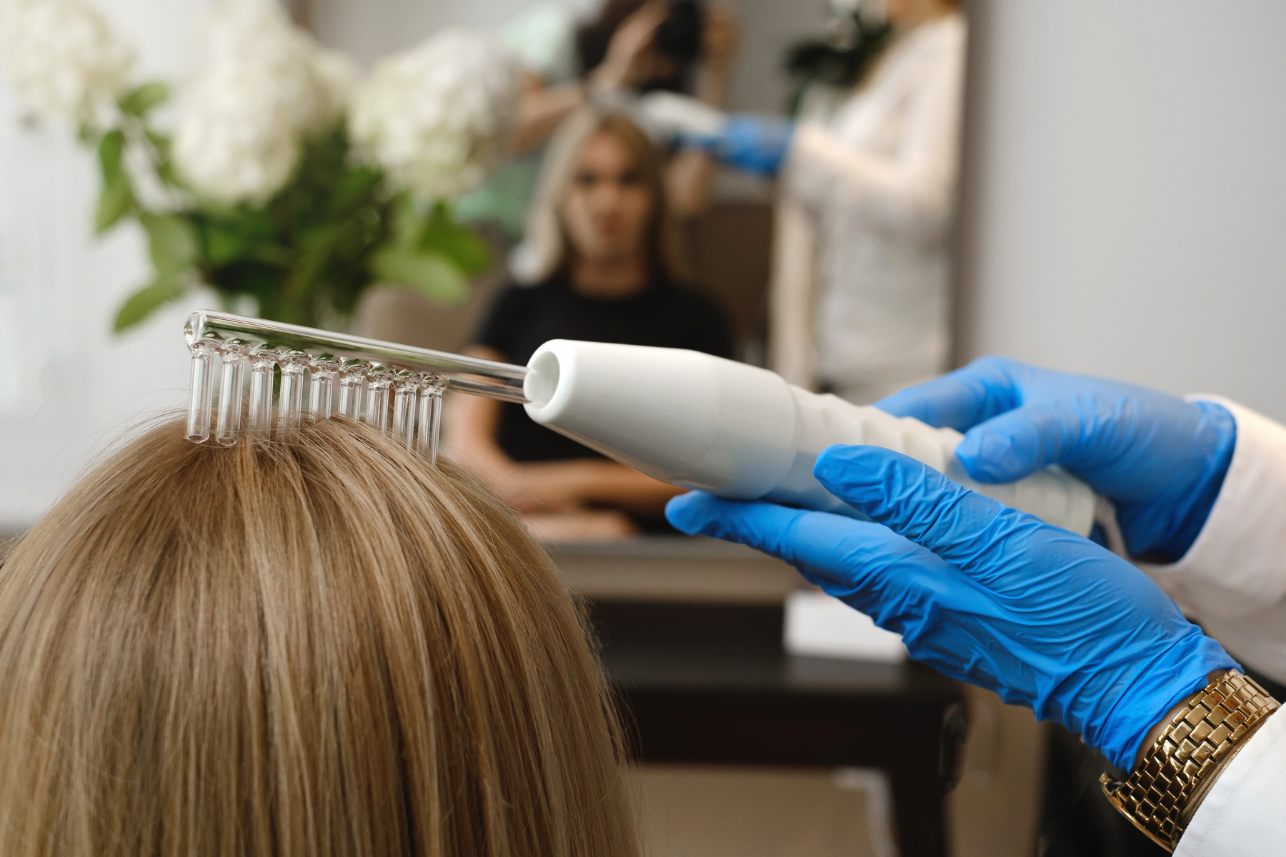 Doctor making hair treatment using Darsonval apparatus at trichologist
