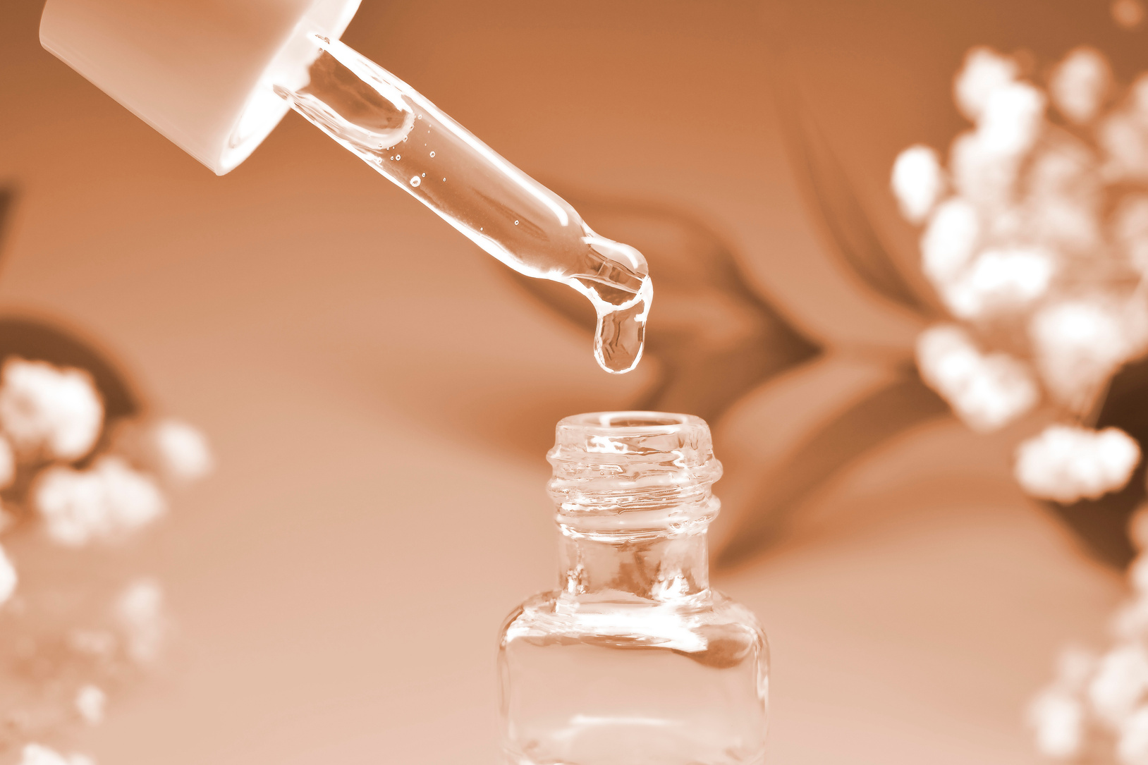 Cosmetic pipette with drops of cosmetic oil close-up on a natural background.